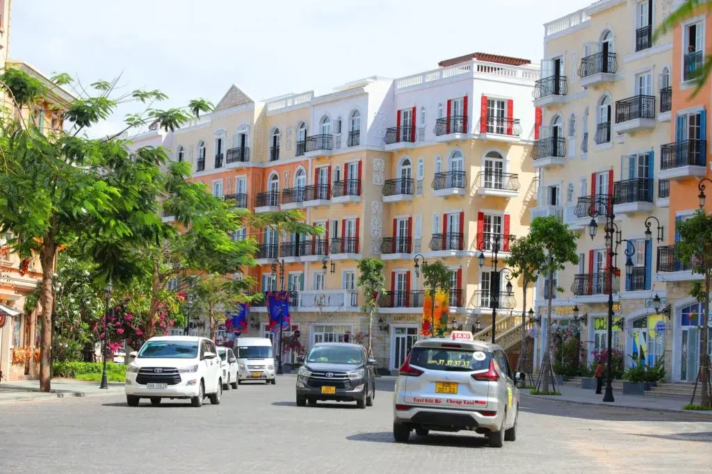 Ảnh phố tại Sunset Town với tường vàng cam, viền trắng, cửa chớp đỏ xanh và lan can sẫm màu